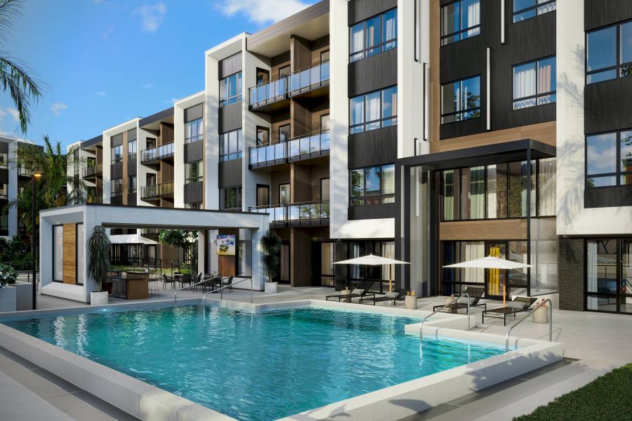 Modern apartment building with balconies, a pool, lounge chairs, umbrellas, and a shaded outdoor area.